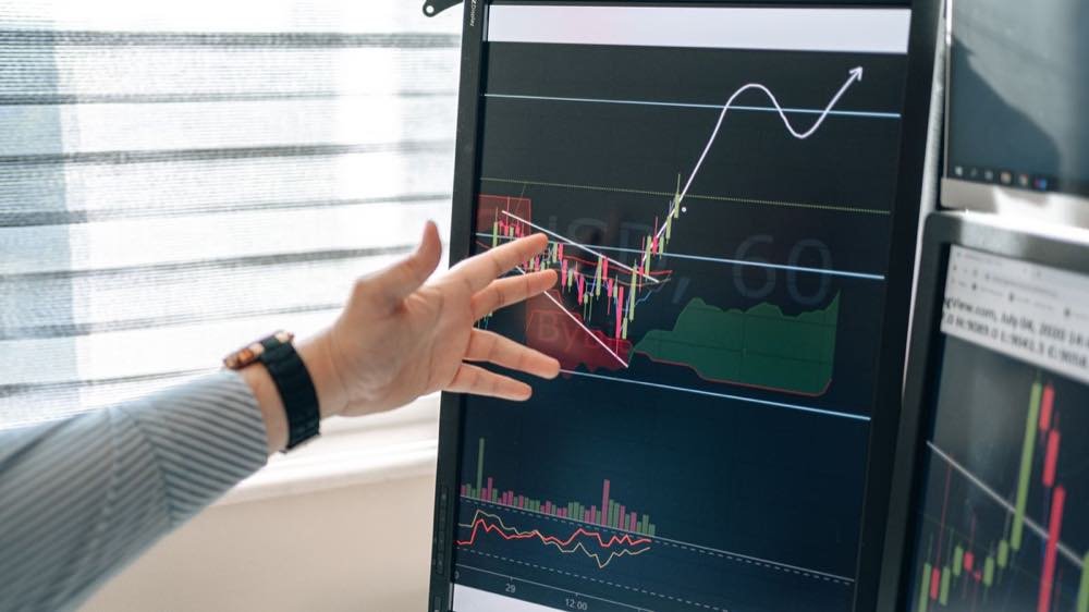 Una mano señalando una curva de rendimiento en un monitor